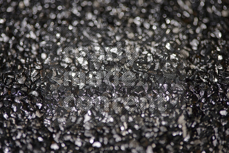 Black shimmering fragments of glass scattered on a black background