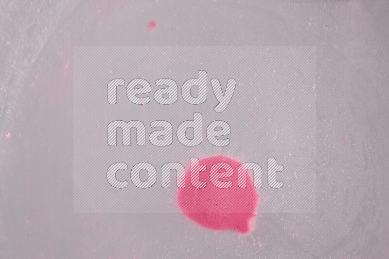 The image captures a dramatic splatter of pink paint over a white backdrop