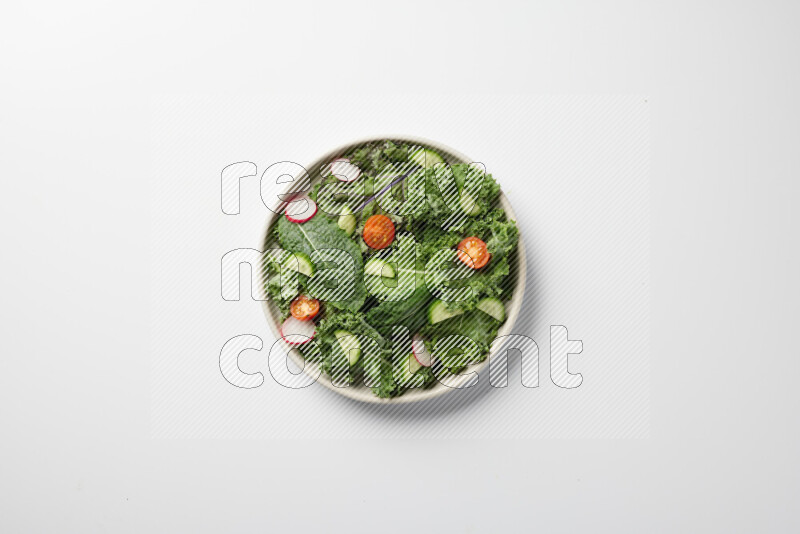 A bowl of fresh vegetables salad with kale leaves, cherry tomatoes, sliced radishes and sliced cucumber on a white background