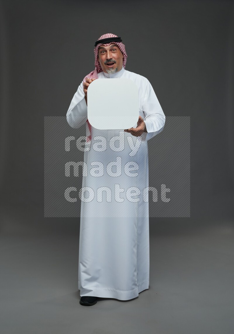 Saudi man with shomag Standing holding social media sing on gray background