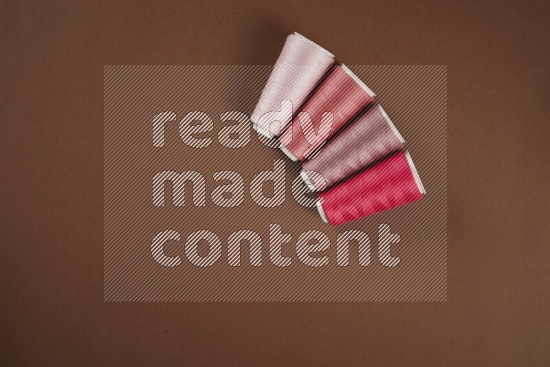 مجموعة من أدوات الخياطة والتفصيل زهرية اللون على خلفية بنية