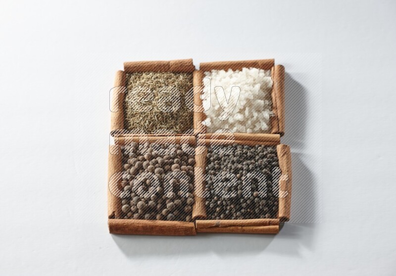 4 squares of cinnamon sticks full of cumin, white salt, allspice and black pepper on white flooring