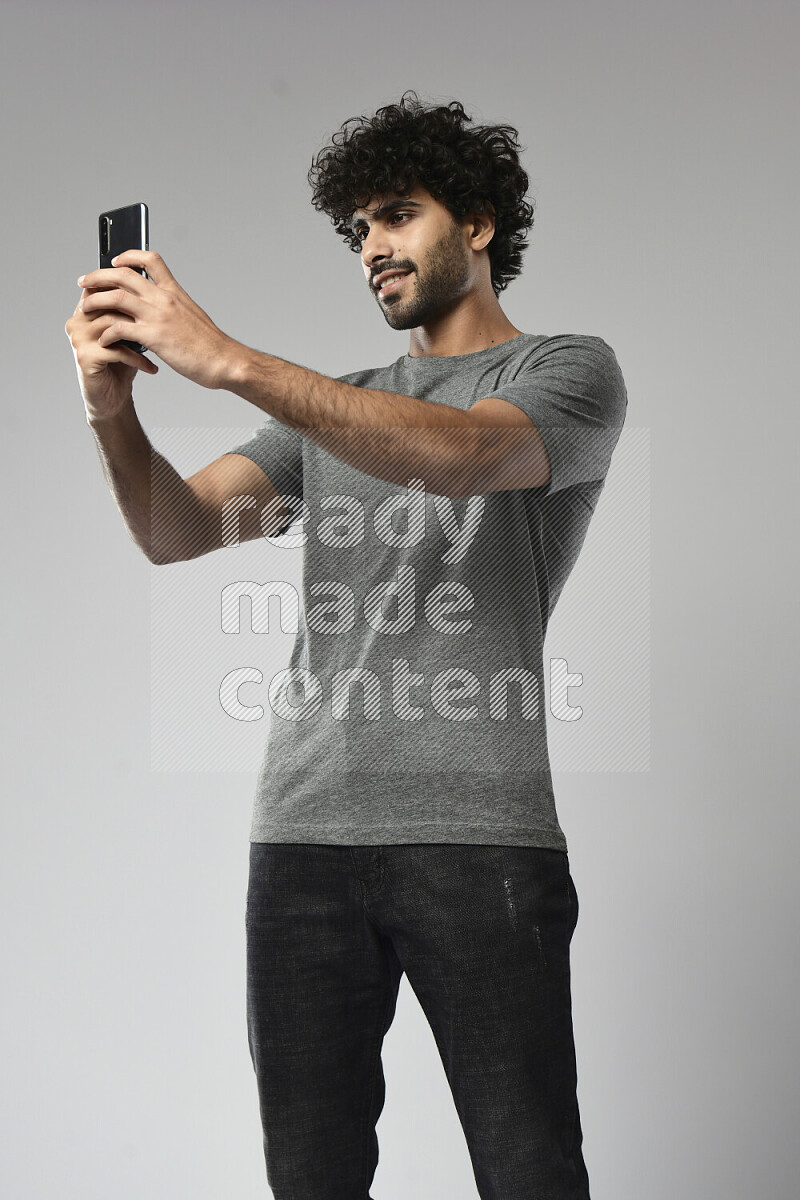 A man wearing casual standing and taking a selfie on white background