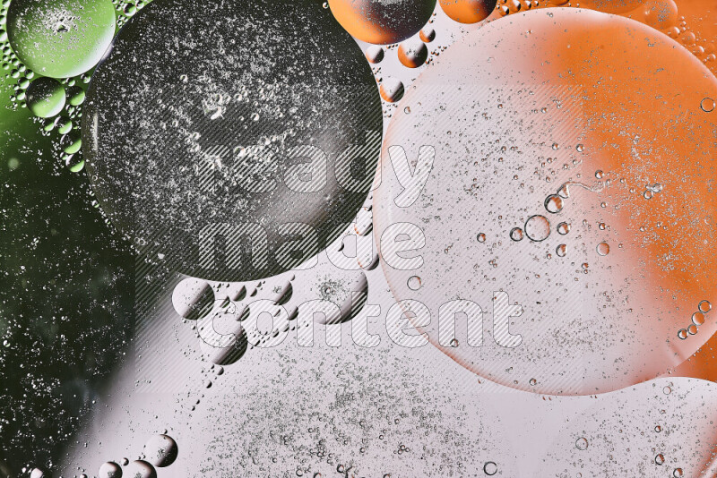 Close-ups of abstract oil bubbles on water surface in shades of orange, green and white