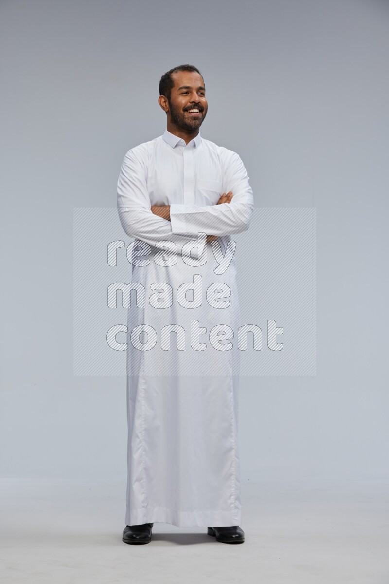 Saudi man wearing Thob standing with crossed arms on Gray background