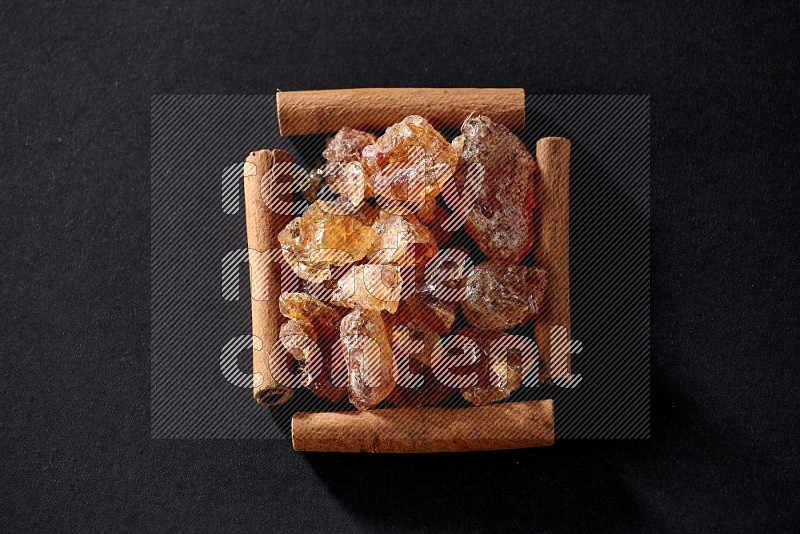 A single square of cinnamon sticks full of Arabic gum on black flooring