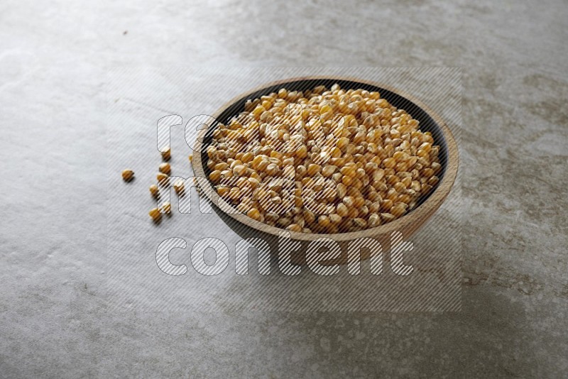 corn kernel in a wooden bowl on a grey textured countertop