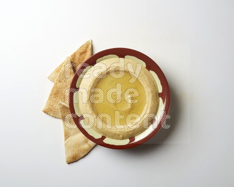 Hummus in a traditional plate garnished with olive oil on a white background