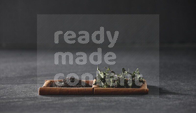 2 squares of cinnamon sticks full of tea and dried mint leaves on black flooring