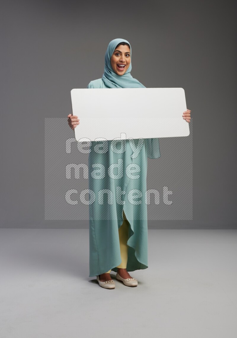 Saudi Woman wearing Abaya standing holding board on Gray background