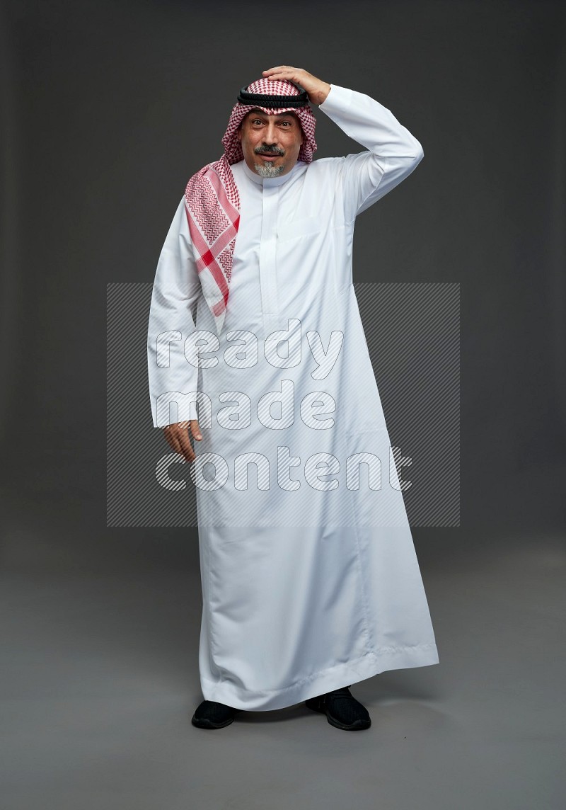 Saudi man with shomag Standing Interacting with the camera on gray background