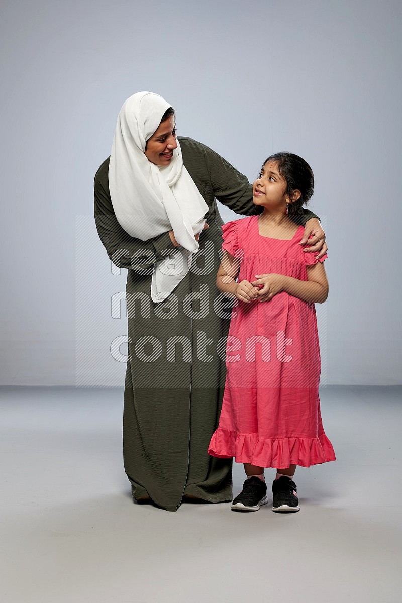 A girl and her mother interacting with the camera on gray background