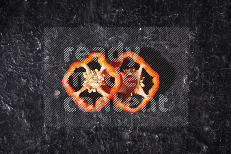 Red bell pepper slices on black background