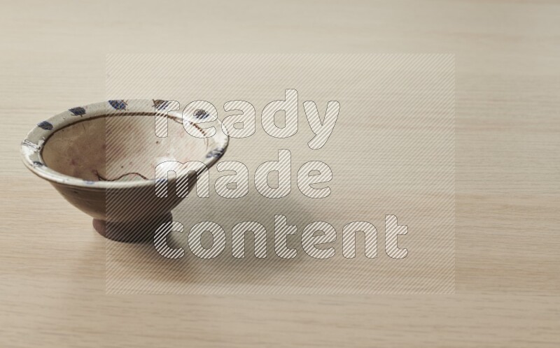A decorative pottery bowl on light wooden background