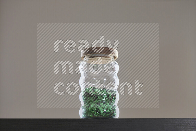 Sequins in a glass jar on black background