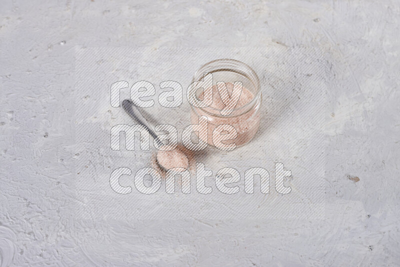 A glass jar full of fine himalayan salt on white background