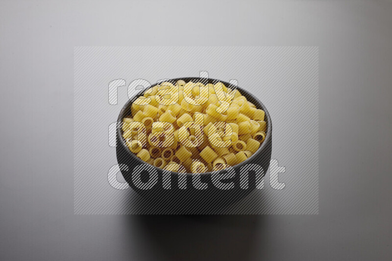 Big rings pasta in a pottery bowl on grey background