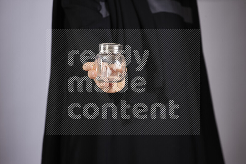 A woman in black abaya holding different glassware in different positions
