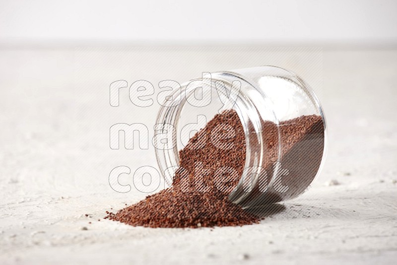 A glass jar full of garden cress and jar is flipped and seeds are spread on a textured white flooring in different angles