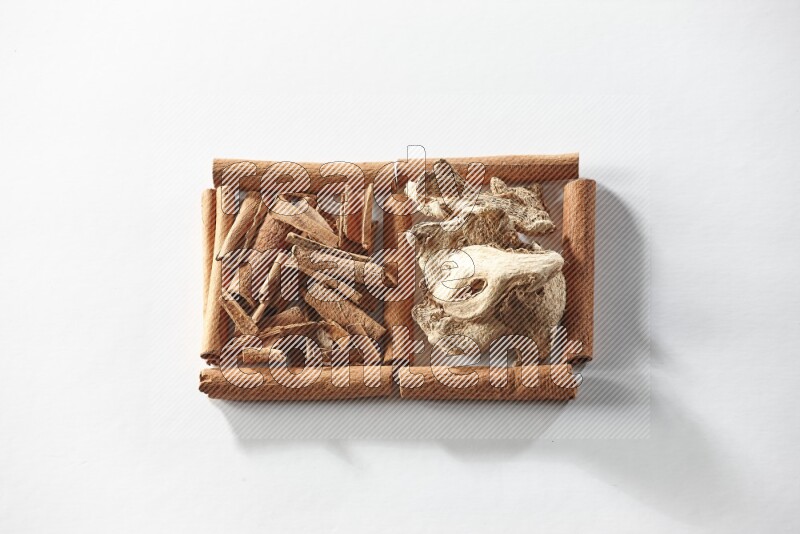 مربعان من أعواد القرفة ممتلئان بقطع من القرفة والزنجبيل المجفف علي خلفية بيضاء