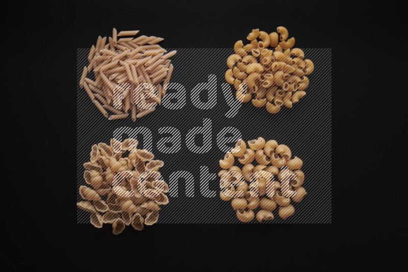 Different pasta types in bunches on black background