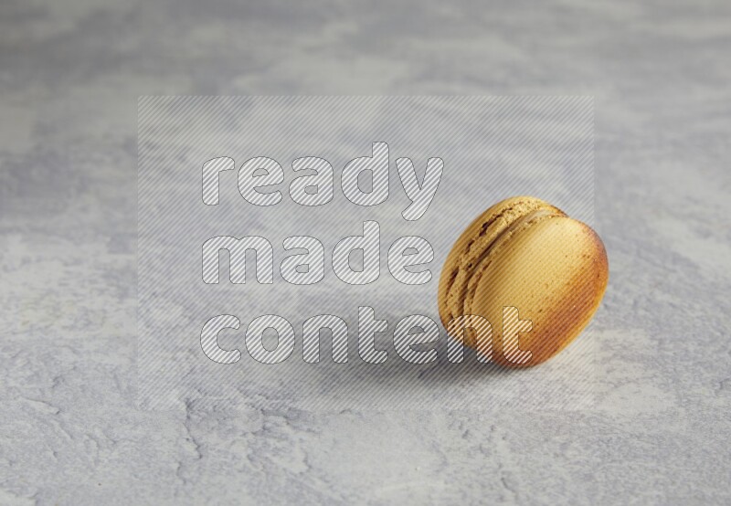 45º Shot of Yellow Crème Brulée macaron on white marble