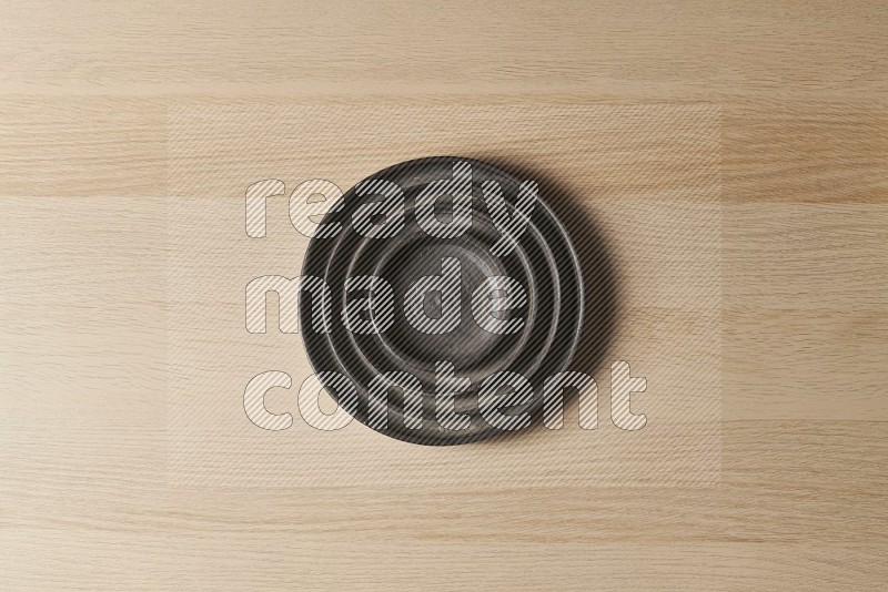 Top View Shot Of A Pottery Ripple Black Plate on Oak Wooden Flooring