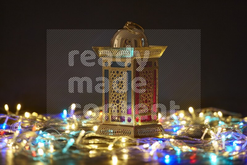 A traditional ramadan lantern surrounded by glowing fairy lights in a dark setup