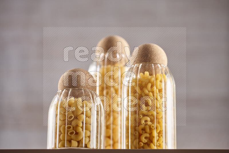 Raw pasta in glass jars on beige background