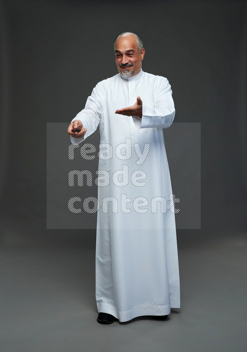 Saudi man without shomag Standing holding car key on gray background