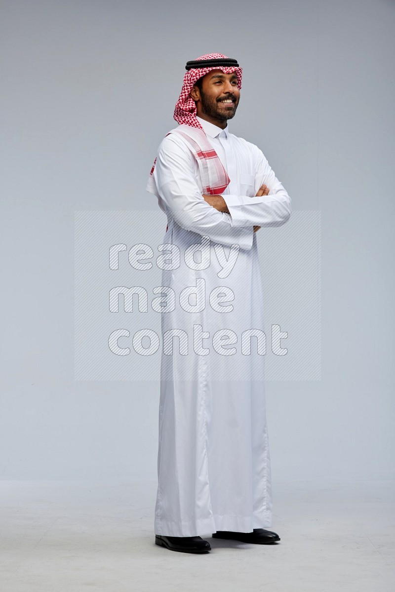 Saudi man Wearing Thob and shomag standing with crossed arms on Gray background