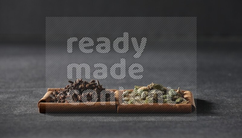 2 squares of cinnamon sticks full of cardamom and cloves on black flooring