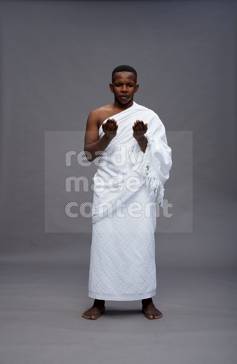 A man wearing Ehram Standing dua'a on gray background