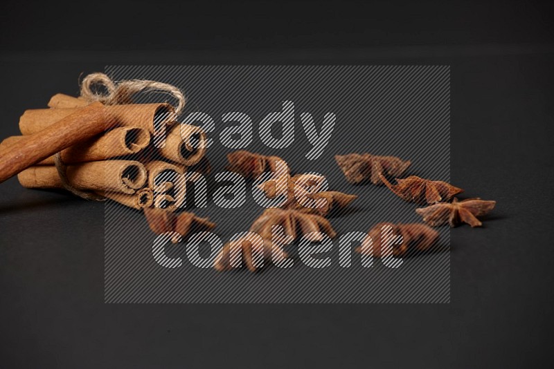 Cinnamon sticks stacked and bounded and star anise on black background