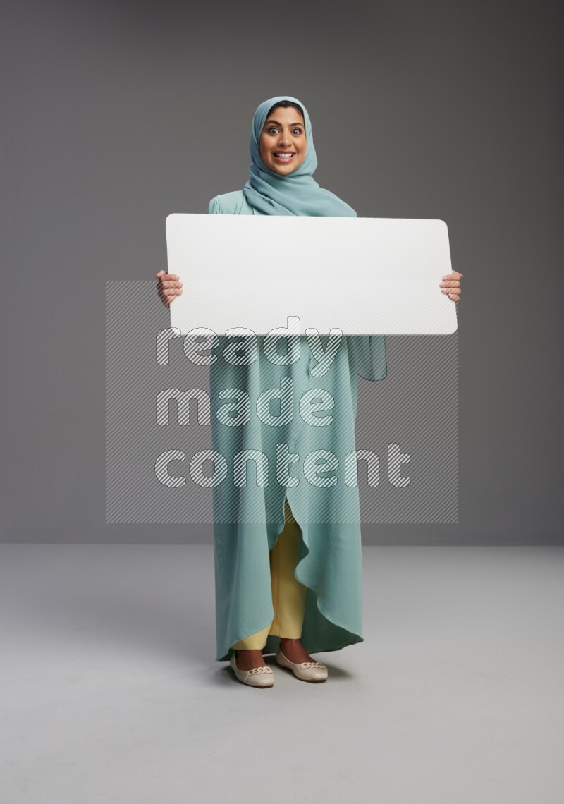 Saudi Woman wearing Abaya standing holding board on Gray background