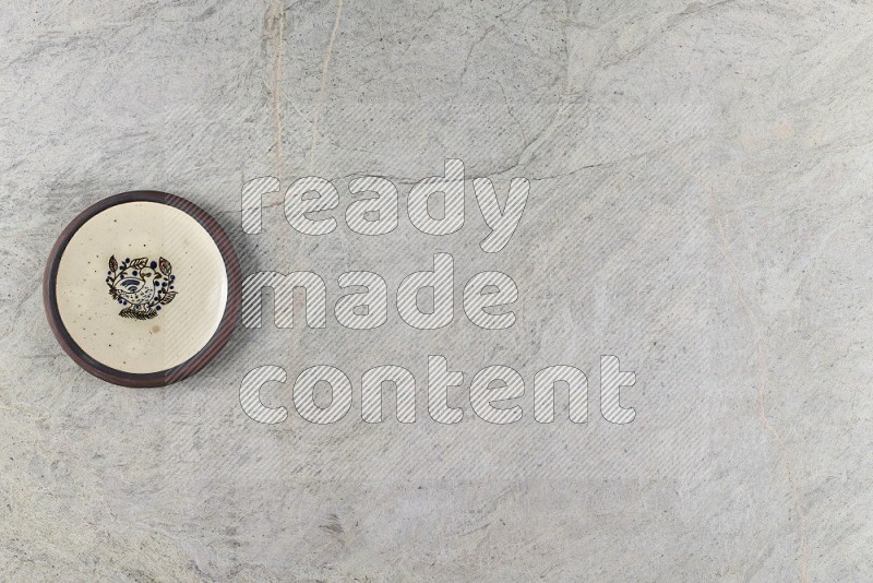 Top View Shot Of A Decorative Pottery Plate On Grey Marble Flooring