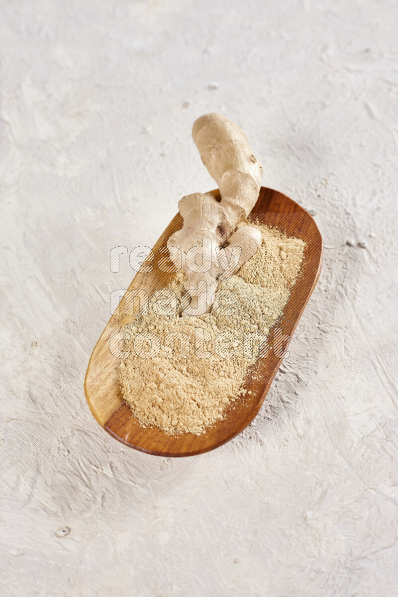 A wooden plate full of ground ginger powder with fresh root in it on white background
