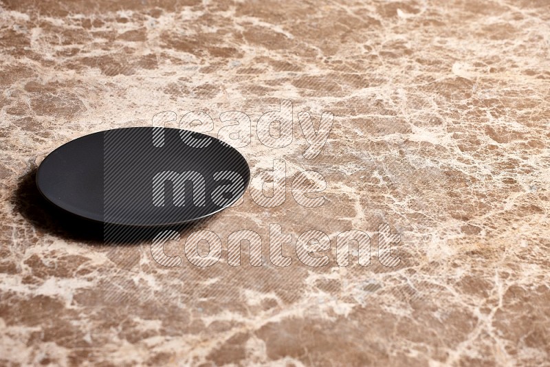 Black Ceramic Circular Plate on Beige Marble Flooring, 45 degrees