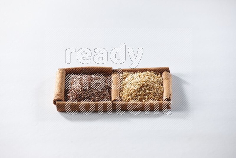 مربعان من أعواد القرفة ممتلئان ببذور الكتان وبذور السمسم علي خلفية بيضاء