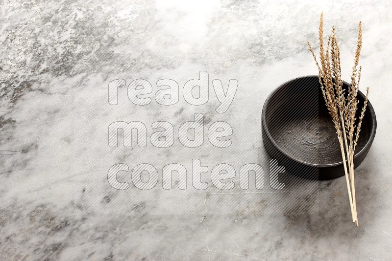 Wheat stalks on Black Pottery Oven Plate on grey marble flooring, 45 degree angel