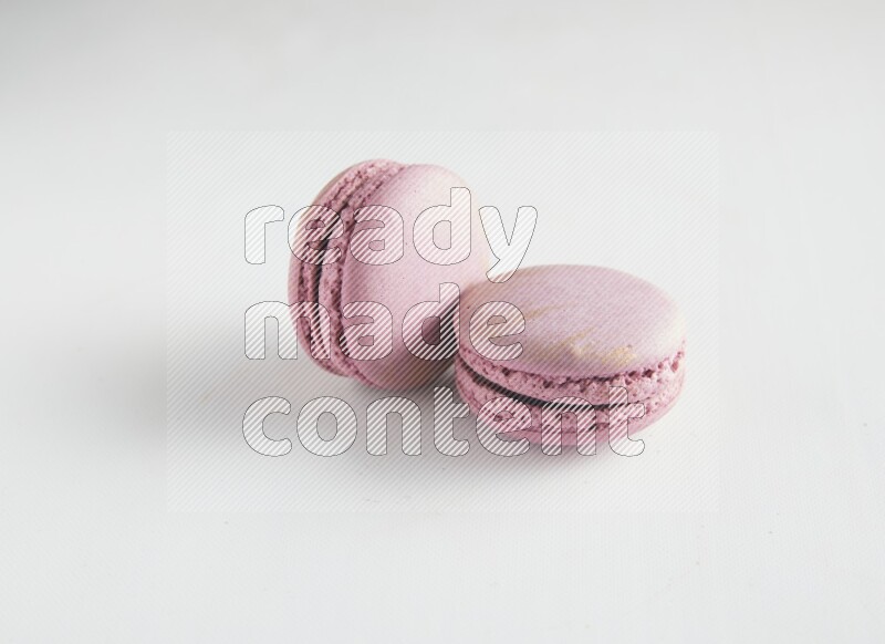 45º Shot of two Purple Strawberry macarons on white background