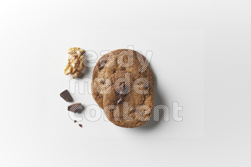 Chocolate chips cookies with chocolate and walnuts beside it on a white background