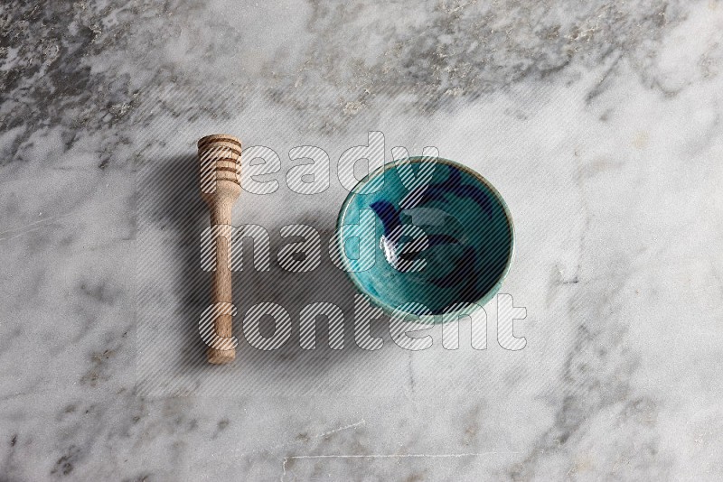 Decorative Pottery bowl with wooden honey handle on the side with grey marble flooring, 65 degree angle