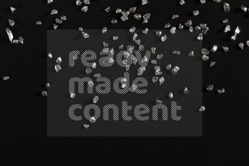 قطع زجاجية فضية لامعة متناثرة على خلفية سوداء