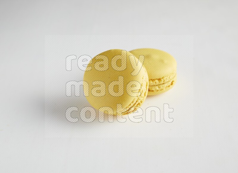 45º Shot of two Yellow Lemon macarons on white background