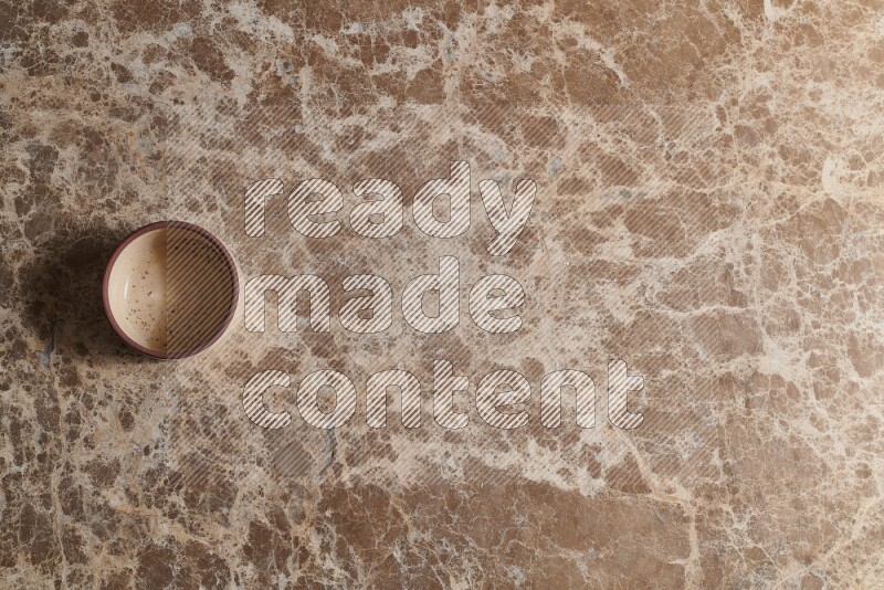 A beige pottery bowl on beige marble background