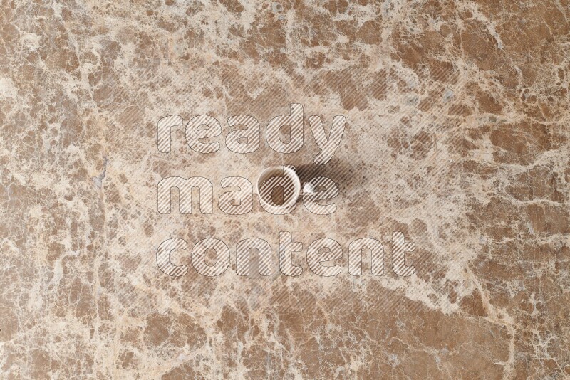 A pottery cup on beige marble background