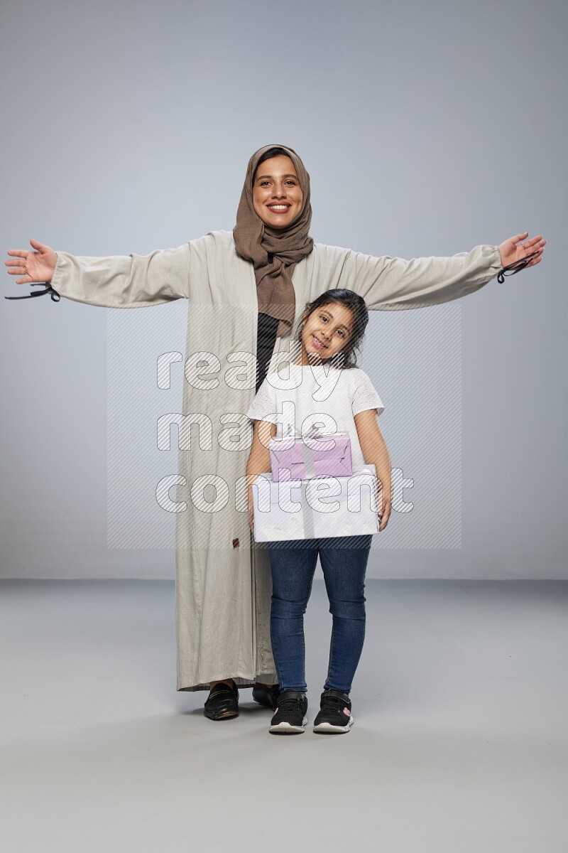 A girl giving a gift to her mother on gray background