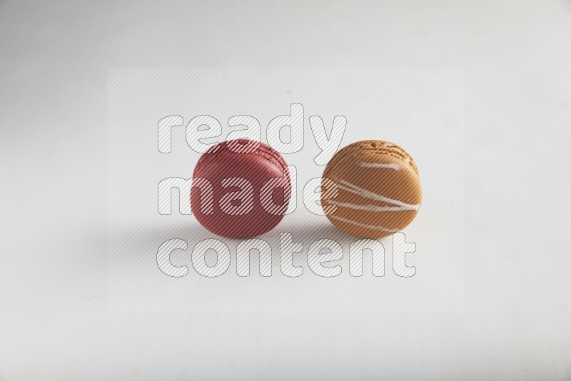 45º Shot of of two assorted Brown Irish Cream, and Red Velvet macarons on white background