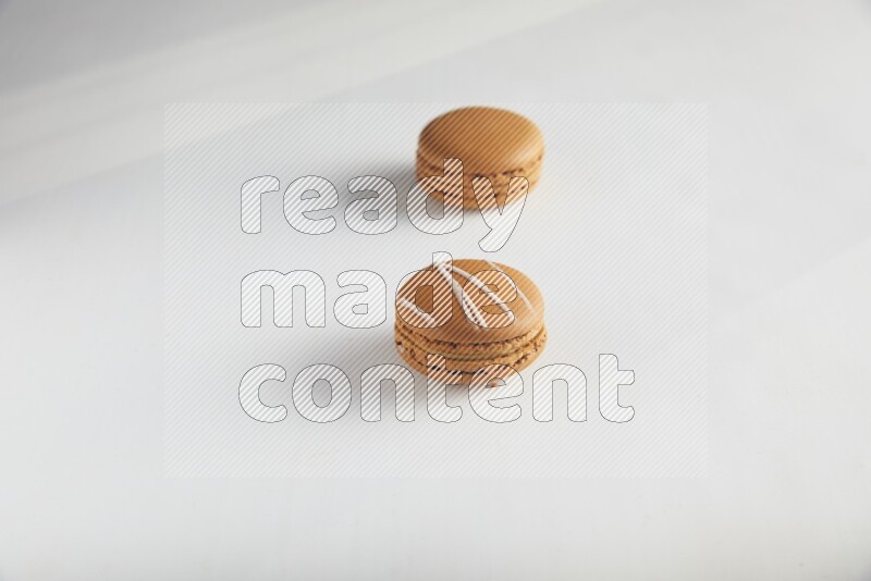 45º Shot of of two assorted Brown Irish Cream, and Brown Maple Taffy macarons  on white background